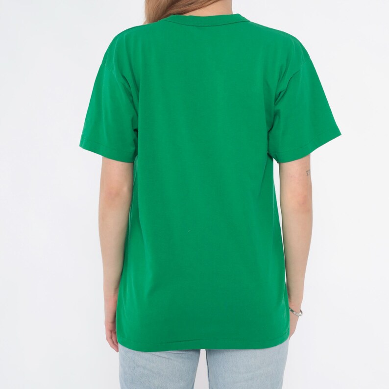 K&ouml;nnte beinhalten: Ein einfarbiges gr&uuml;nes T-Shirt mit kurzen &Auml;rmeln. Die R&uuml;ckansicht des T-Shirts zeigt ein schlichtes, klassisches Design. Das Shirt ist aus einem weichen Material und hat einen leuchtenden Gr&uuml;nton.