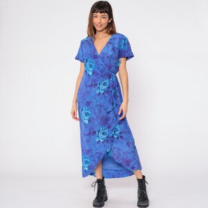 May include: A blue maxi dress with a floral print and a wrap style. The dress has a V-neckline and short sleeves. The dress is tied at the waist with a sash.