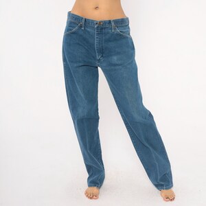 May include: Blue denim jeans with a classic five-pocket design. The jeans have a straight leg cut and a button and zipper closure. The denim has a medium wash and a slightly faded appearance.