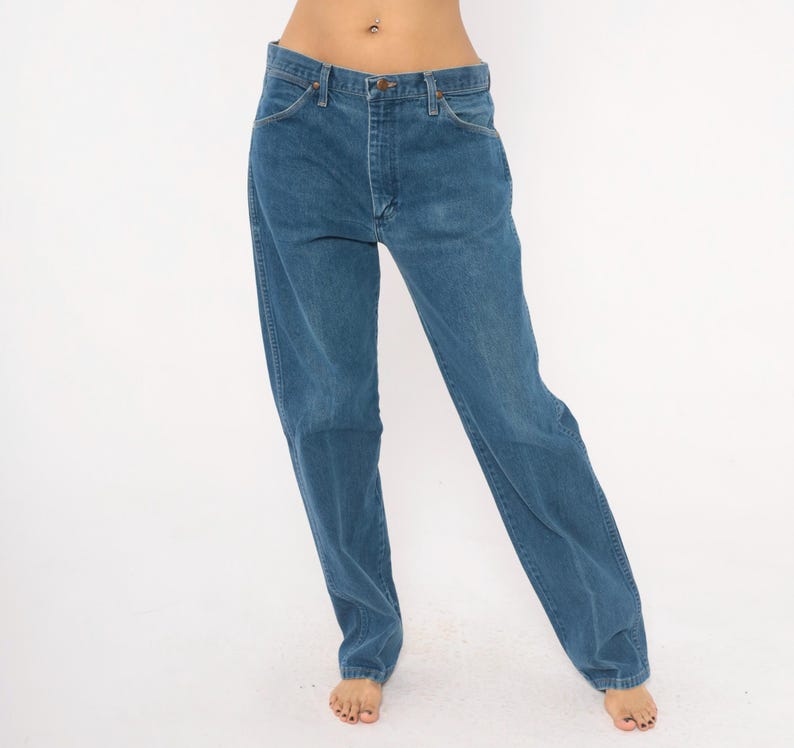 May include: Blue denim jeans with a classic five-pocket design. The jeans have a straight leg cut and a button and zipper closure. The denim has a medium wash and a slightly faded appearance.
