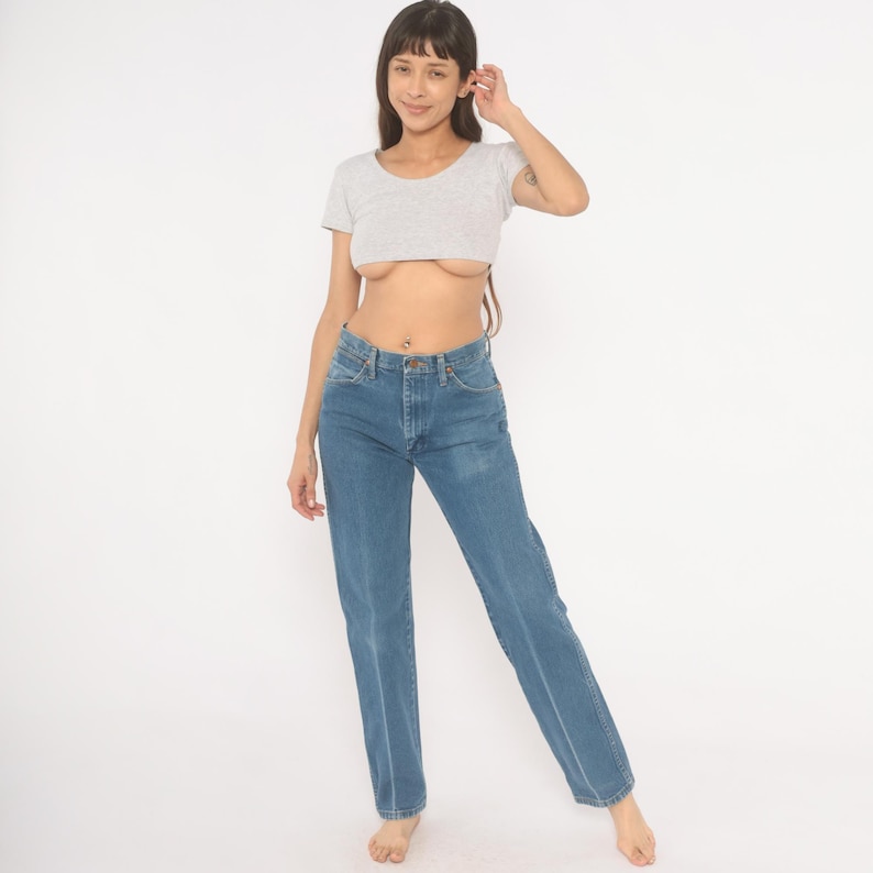 May include: A light gray crop top and blue jeans. The short-sleeved top has a scoop neck. The jeans are a medium wash with a straight leg and a button and zipper closure.