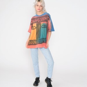 May include: A tie-dye t-shirt with a colorful graphic of the Rolling Stones logo and the text "Voodoo Lounge".