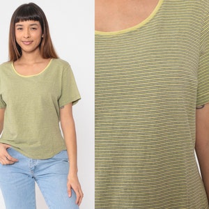 Peut inclure: T-shirt &agrave; manches courtes ray&eacute; vert et gris avec un col jaune. Le t-shirt a une encolure arrondie et une coupe d&eacute;contract&eacute;e. Le tissu semble &ecirc;tre une mati&egrave;re douce et l&eacute;g&egrave;re.