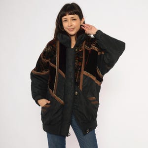 May include: Black and brown vintage jacket with a high collar. The jacket features a mix of textures, including quilted fabric, velvet, and patterned panels. Gold trim accents the design. The jacket has a button closure and pockets.