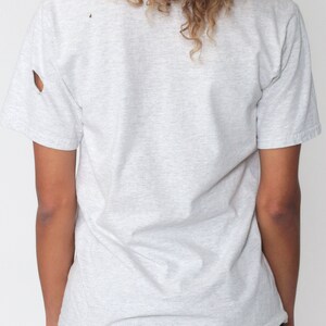 May include: A gray short-sleeved t-shirt with a distressed look. The shirt has a small hole near the shoulder seam.