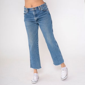 May include: A pair of light blue denim jeans with a frayed hem. The jeans have a high waist and a straight leg.