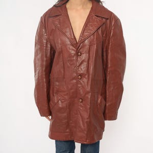 May include: A brown leather jacket with a notched collar, three buttons, and two front pockets. The jacket has a classic, vintage style and is made of a smooth, textured leather material.