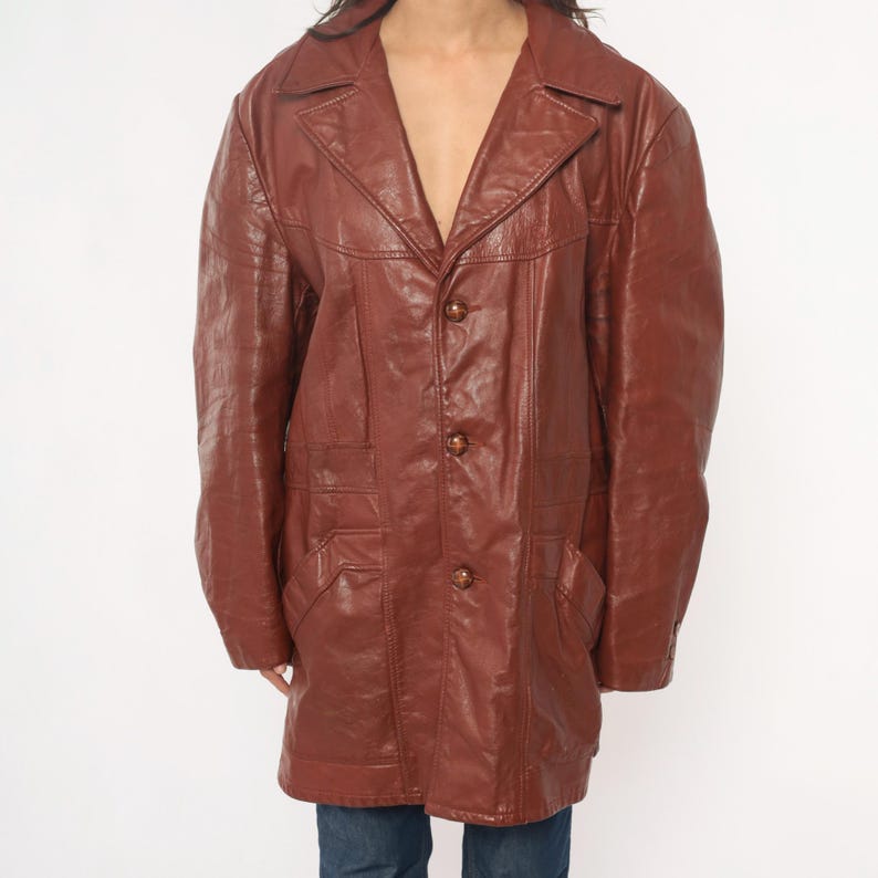 May include: A brown leather jacket with a notched collar, three buttons, and two front pockets. The jacket has a classic, vintage style and is made of a smooth, textured leather material.