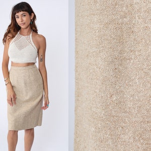 May include: A beige pencil skirt with a textured fabric. The skirt is knee-length and has a straight silhouette.