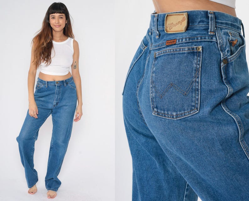 May include: A pair of blue denim jeans with a high waist and a wide leg. The jeans have a Wrangler logo on the back pocket.