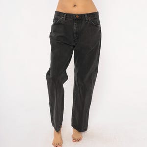 May include: A pair of black denim jeans. The jeans have a classic five-pocket design, a button and zipper closure, and a straight leg fit. The denim appears to be slightly faded, giving them a vintage look.