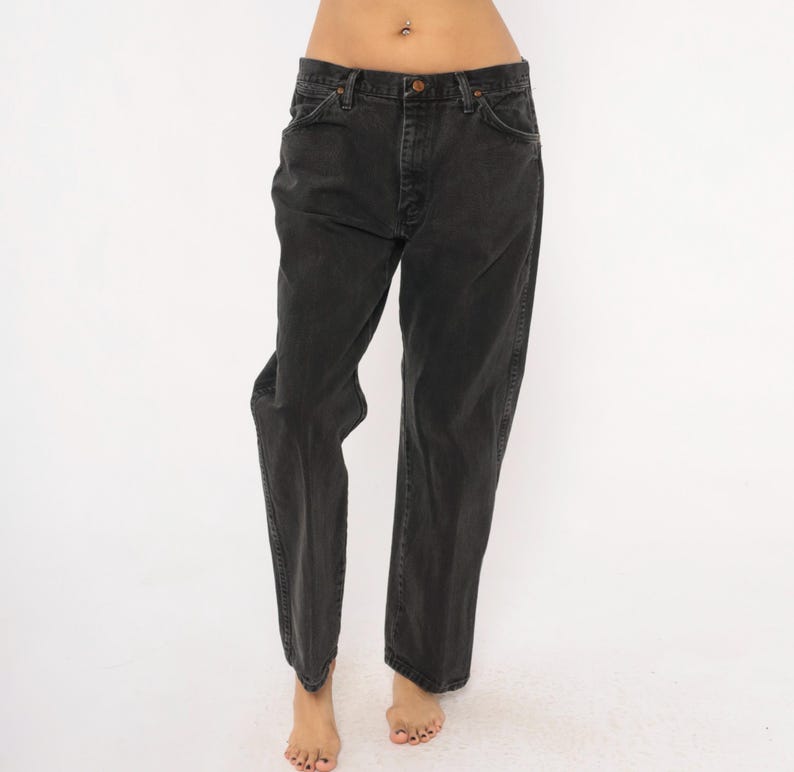 May include: A pair of black denim jeans. The jeans have a classic five-pocket design, a button and zipper closure, and a straight leg fit. The denim appears to be slightly faded, giving them a vintage look.