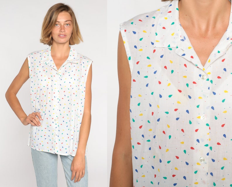 May include: White sleeveless button-down shirt with a colorful teardrop pattern. The shirt has a collar and buttons down the front. The teardrops are red, yellow, blue, and green.