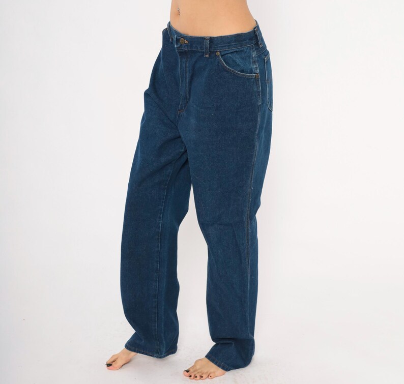 May include: Dark blue denim jeans with a classic five-pocket design. The jeans have a straight leg cut and a button and zipper closure. The fabric appears to be a medium-weight denim, suitable for everyday wear. The jeans are shown against a plain white background.