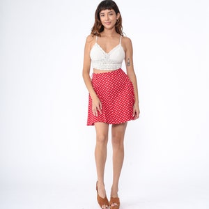 Peut inclure: Une jupe mini &agrave; pois rouges avec un haut en crochet blanc. La jupe a une fermeture &agrave; boutons et une silhouette &eacute;vas&eacute;e.