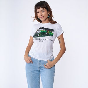 Può includere: Maglietta bianca con un grafico di un treno verde e nero e il testo "SOUTHERN RAILWAY 4501".