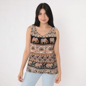 May include: A sleeveless tank top with a black base, featuring a repeating pattern of elephants in tan and orange. The top has a V-neck and a decorative border, with a mix of geometric and floral designs.
