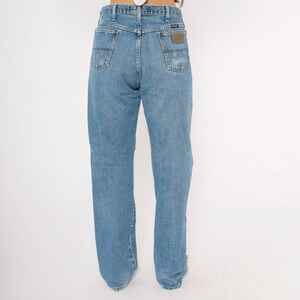 Pu&ograve; includere: Jeans in denim blu chiaro con un classico design a cinque tasche. I jeans hanno un taglio dritto e una toppa in pelle marrone sulla tasca posteriore. I jeans sono realizzati in resistente denim.