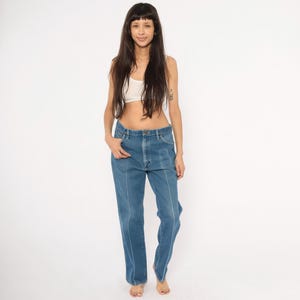 Peut inclure: Jean en denim bleu avec des coutures blanches. Le jean a une conception classique &agrave; cinq poches et une coupe droite. Le mod&egrave;le porte un crop top blanc.