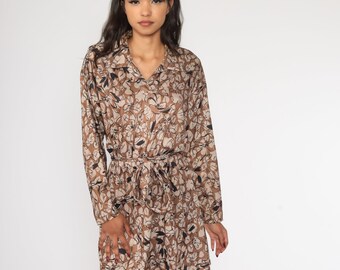 May include: A brown and white floral print shirt dress with a long sleeve and a tie belt.