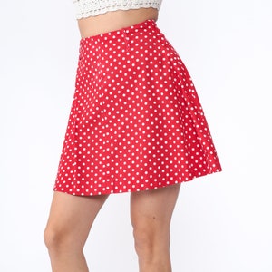 Peut inclure: Une jupe rouge &agrave; pois blancs. La jupe est trap&egrave;ze et a une taille haute.