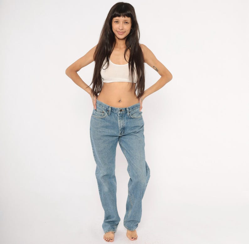 Peut inclure: Jean en denim bleu clair avec une conception classique &agrave; cinq poches. Le jean a une fermeture &agrave; bouton et &agrave; glissi&egrave;re et une coupe droite. Le mod&egrave;le porte un haut court blanc.