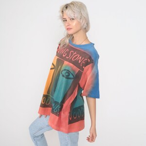 May include: A tie-dye t-shirt with a colorful abstract design and the text "Rolling Stones" printed on the front.