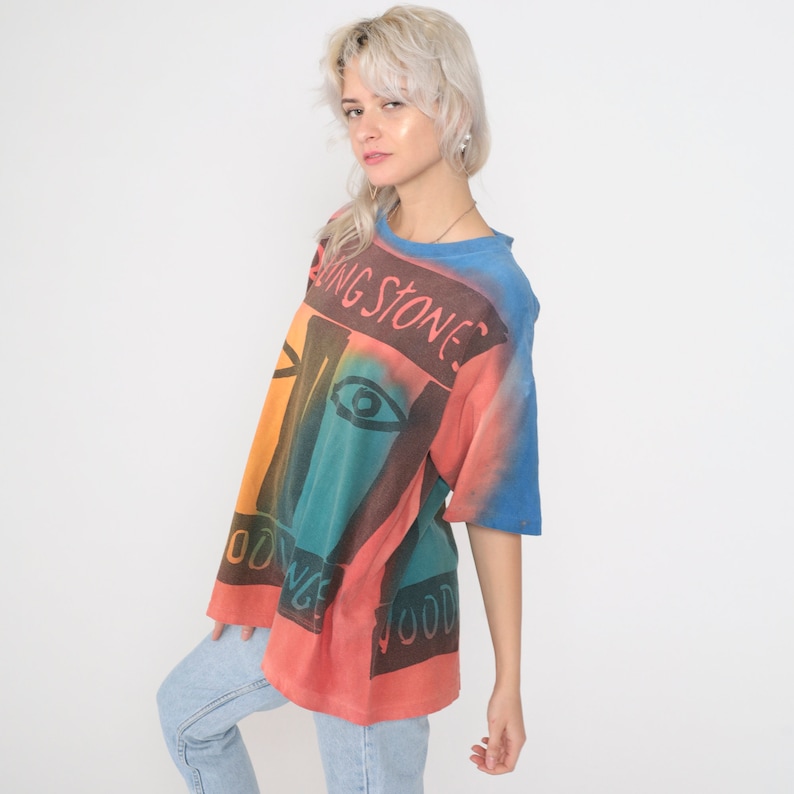 May include: A tie-dye t-shirt with a colorful abstract design and the text "Rolling Stones" printed on the front.