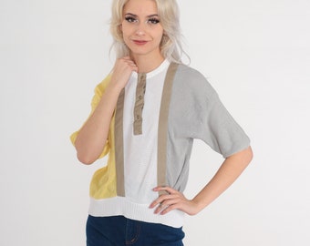 May include: A white, yellow and grey striped knit shirt with a button-up collar and short sleeves.