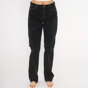 May include: Black denim jeans with a classic five-pocket design. The jeans have a straight leg cut and a button and zip closure. The denim appears slightly faded, giving them a worn-in look. A versatile wardrobe staple.