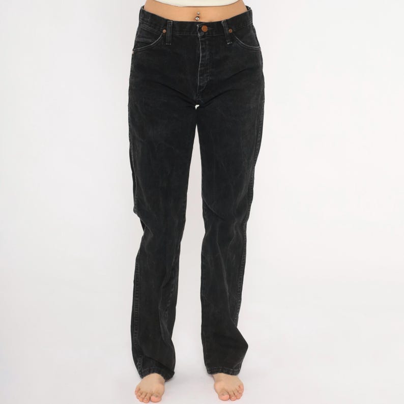 May include: Black denim jeans with a classic five-pocket design. The jeans have a straight leg cut and a button and zip closure. The denim appears slightly faded, giving them a worn-in look. A versatile wardrobe staple.