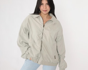 May include: A light gray zip-up jacket with a stand-up collar. The jacket has a zipper closure and two pockets on the front.