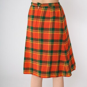May include: A knee-length skirt with a plaid pattern in orange, green, and brown.