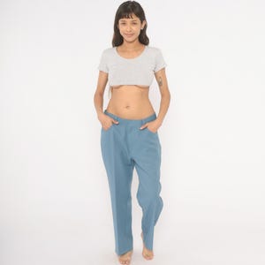 May include: A light gray crop top and blue pants. The top is short-sleeved and the pants are a solid blue color. The pants have a straight leg design.