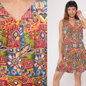 May include: A sleeveless mini dress with a colorful geometric print in shades of red, yellow, green, and blue. The dress has a V-neckline and a button-up front.