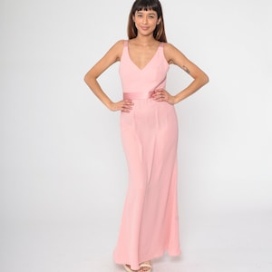 May include: A long pink maxi dress with a V-neckline and a matching pink satin sash.