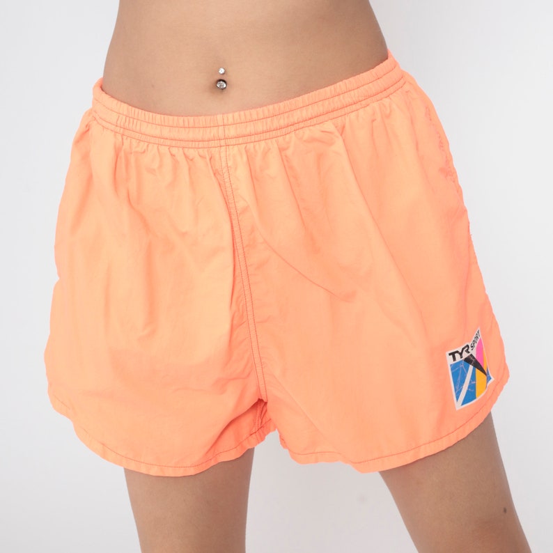 May include: Orange swimming shorts with a TYR Sport logo on the right leg.