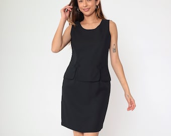 May include: A sleeveless black dress with a scoop neckline and a fitted silhouette. The dress features a peplum detail at the waist and two small pockets. The dress is knee-length and made of a solid black fabric.