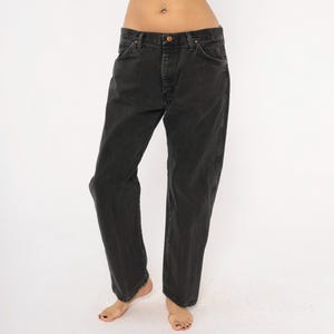 May include: Black denim jeans with a classic five-pocket design. The jeans have a button and zipper closure and a straight leg fit. The dark wash denim has a slightly faded appearance. The jeans are a versatile wardrobe staple.