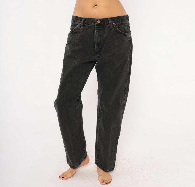 May include: Black denim jeans with a classic five-pocket design. The jeans have a button and zipper closure and a straight leg fit. The dark wash denim has a slightly faded appearance. The jeans are a versatile wardrobe staple.