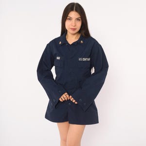 May include: A dark navy blue long-sleeve button-up shirt featuring a collar, two chest pockets, and buttoned cuffs. The text "BIGGS" is embroidered on the right chest, and "U.S. COAST GUARD" is embroidered on the left chest in white lettering.
