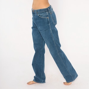 May include: Blue denim jeans with a classic five-pocket design. The jeans have a straight leg cut and a medium wash. The image shows the jeans from the waist down, with a white background.