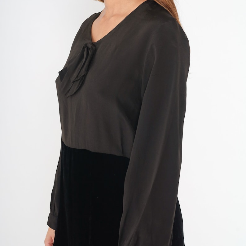 May include: A black long-sleeved dress with a velvet skirt and a bow detail at the neckline.
