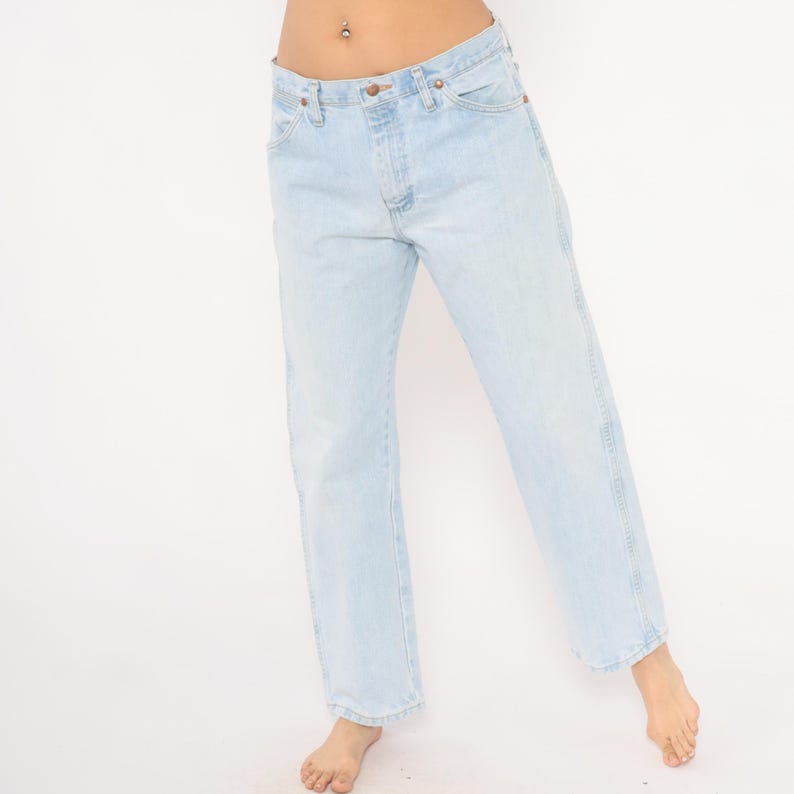 May include: Light blue denim jeans with a classic five-pocket design. The jeans have a straight leg cut and a faded wash, giving them a vintage look. The jeans are made of a sturdy denim material.