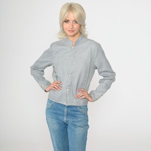 May include: A light gray collared shirt with long sleeves and a button-up front. The shirt has a slightly fitted silhouette and is made of a soft, textured fabric.