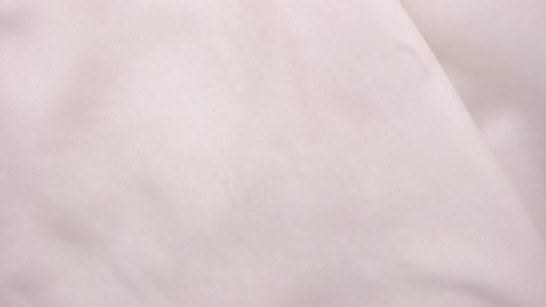 Puede incluir: Primer plano de una tela rosa p&aacute;lido, mostrando pliegues y sombras sutiles. El material parece suave y posiblemente ligero, creando una textura suave y fluida. La impresi&oacute;n general es de delicada simplicidad.