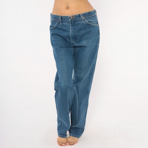 May include: Blue denim jeans with a classic five-pocket design. The jeans have a straight leg cut and a button and zipper closure. The denim has a medium wash and a slightly faded appearance.