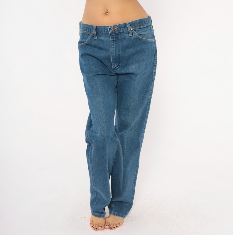 May include: Blue denim jeans with a classic five-pocket design. The jeans have a straight leg cut and a button and zipper closure. The denim has a medium wash and a slightly faded appearance.