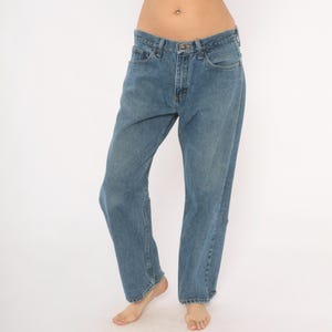 May include: Light blue denim jeans with a classic five-pocket design. The jeans have a straight leg fit and a button and zipper closure. The denim has a faded wash, giving them a worn-in look. The jeans are a casual style.