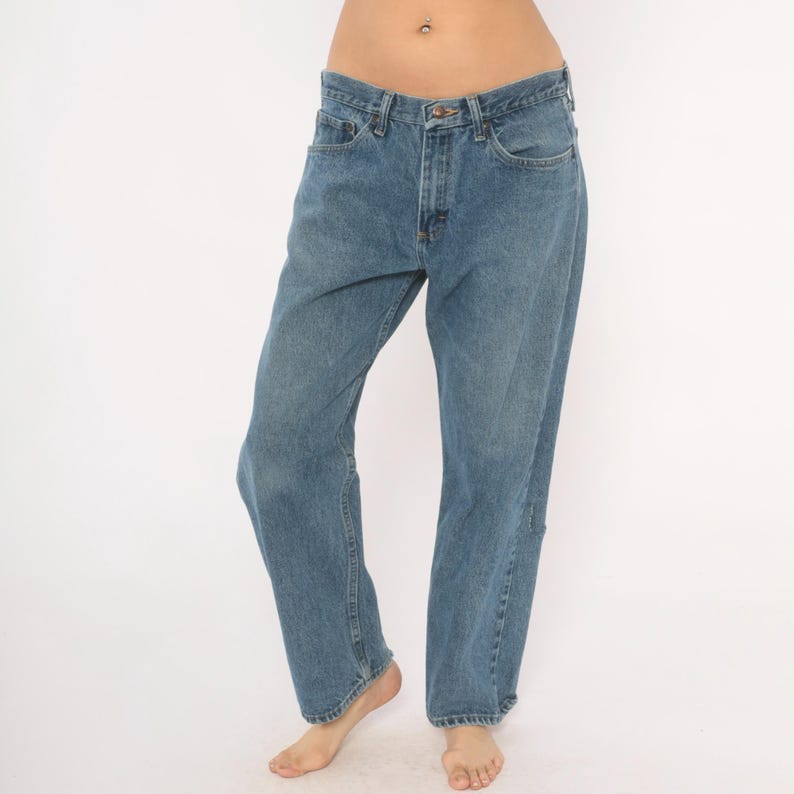 May include: Light blue denim jeans with a classic five-pocket design. The jeans have a straight leg fit and a button and zipper closure. The denim has a faded wash, giving them a worn-in look. The jeans are a casual style.